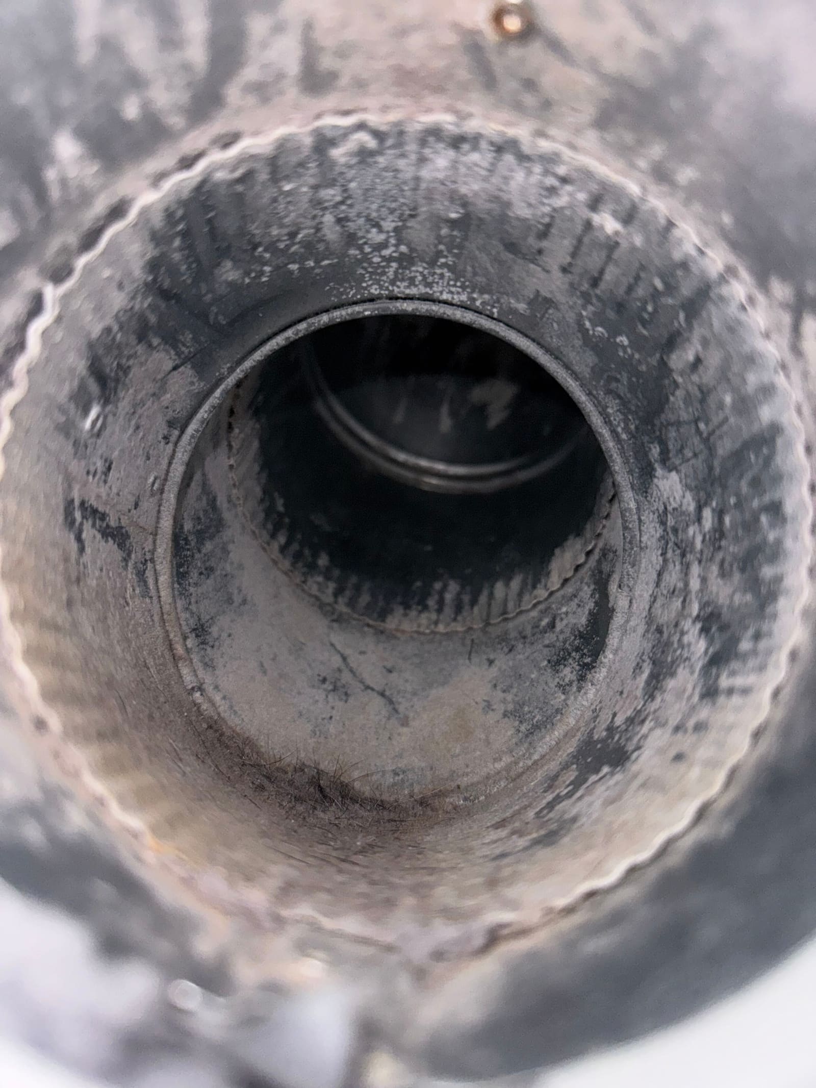 Interior of a dryer duct after cleaning, with bare metal walls and the full diameter restored.