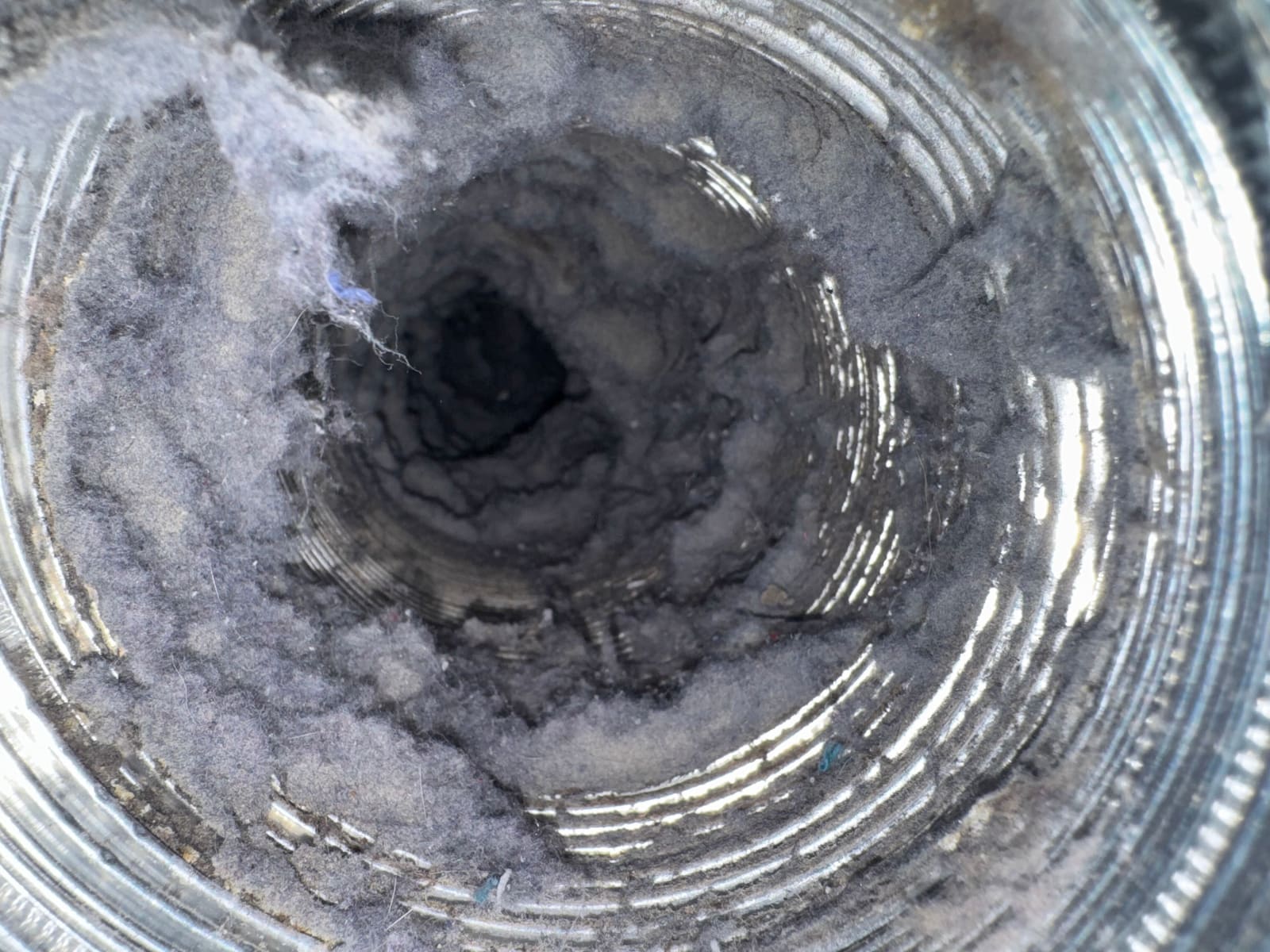 Heavy grey lint accumulation coating the full interior circumference of a dryer duct.